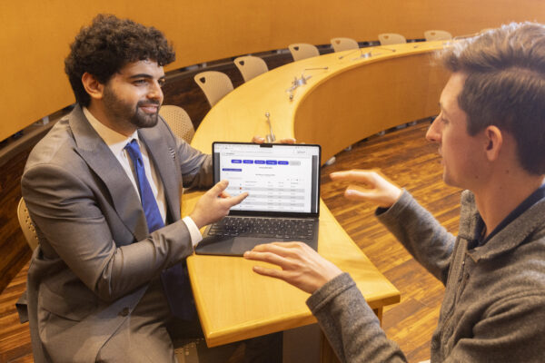 K5125 Sam Hieken in Joslin Senate Chamber Two men sit at a conference table and review information on a laptop.