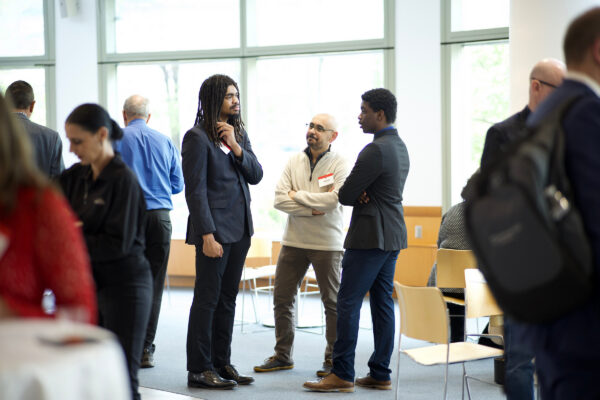 20250429_K9526_031 A group of individuals network and talk at an event.