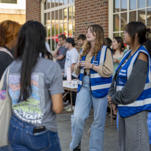 Q0226 CEC Party on the Patio Two Engineers without Borders volunteers talk to an interested crowd gathered around a poster board display.