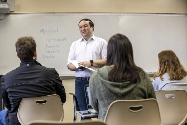 R0922 MUM campus and class A man talks to a group of students in a classroom.